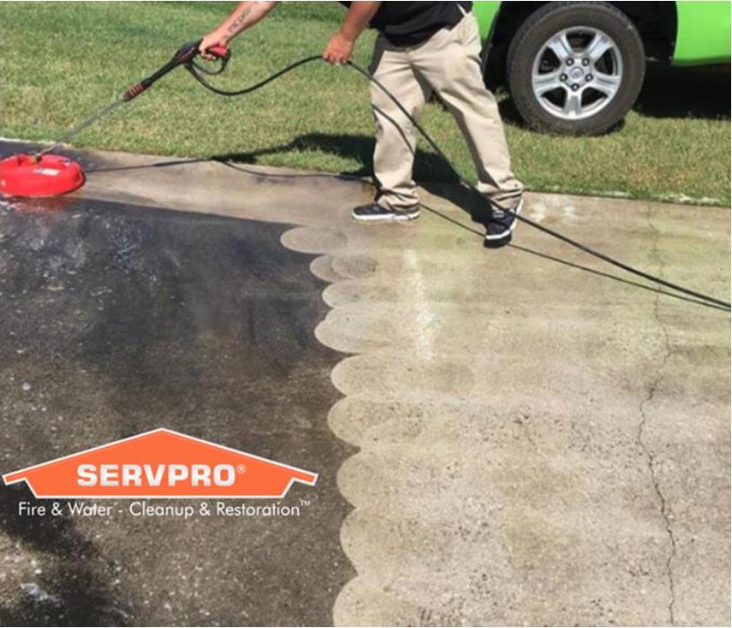 A SERVPRO Production Technician is cleaning a driveway.