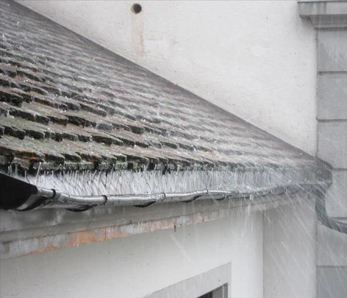 A roof may be seen with leaks in it, causing water to fall down from the heavy rains.